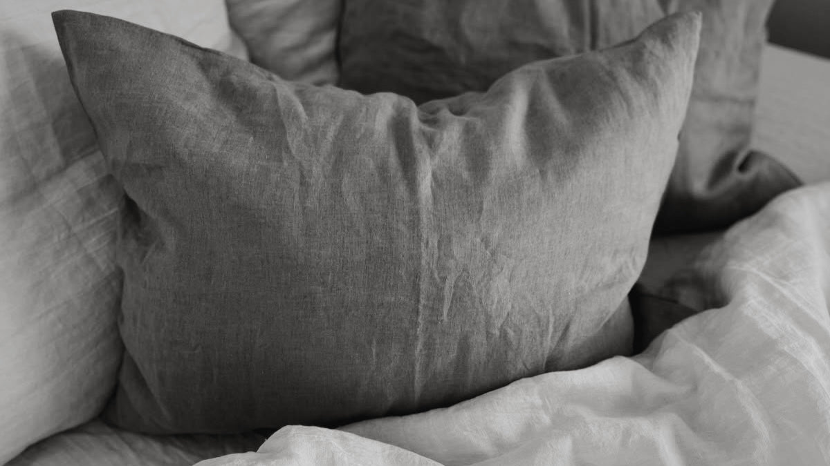 Gray pillows on a bed with light bedding