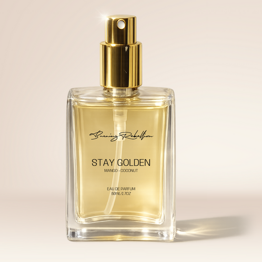 Perfume bottle labeled 'Stay Golden' with gold cap on a beige background